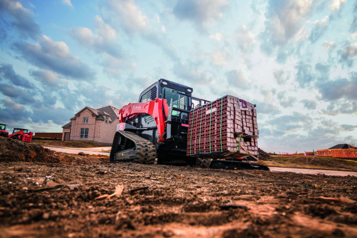 A Kubota SVL97-2 loads a palette of bricks